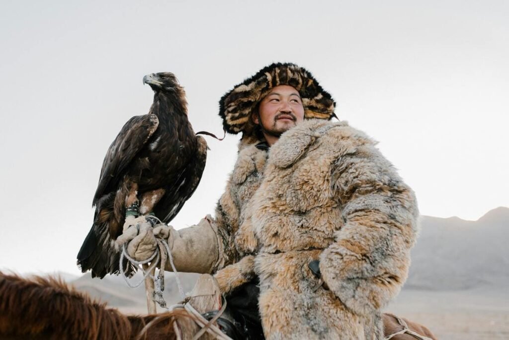 Guide Mongol sur son cheval avec un aigle et un épais manteau de fourrure