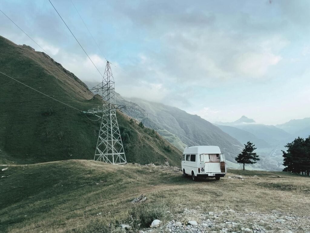 Véhicule aménagé autonome en électricité à côté d'un pylône électrique